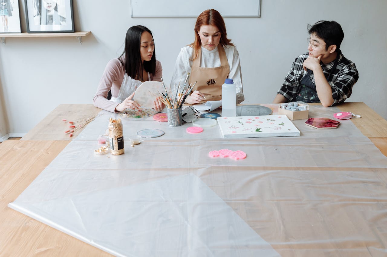 Women and man engaged in a lively art class, learning with brushes and canvas.