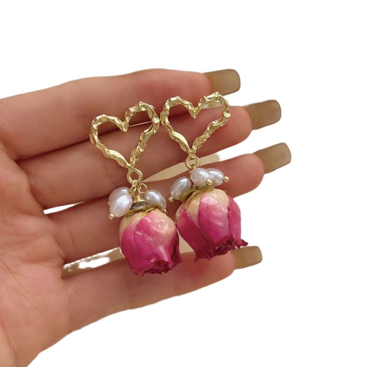 Close up of gold heart pearl preserved rose drop earrings